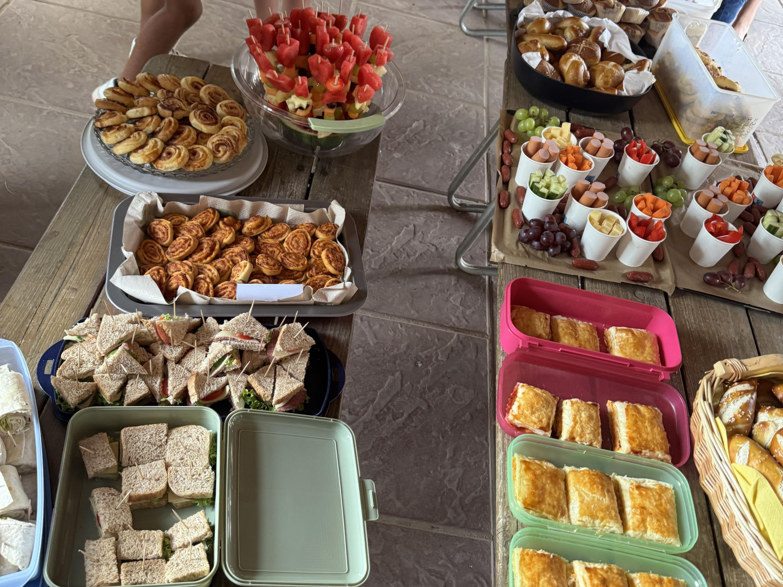 Tische mit verschiedenen Snacks und Speisen, darunter Gebäck, belegte Brote und Obst.